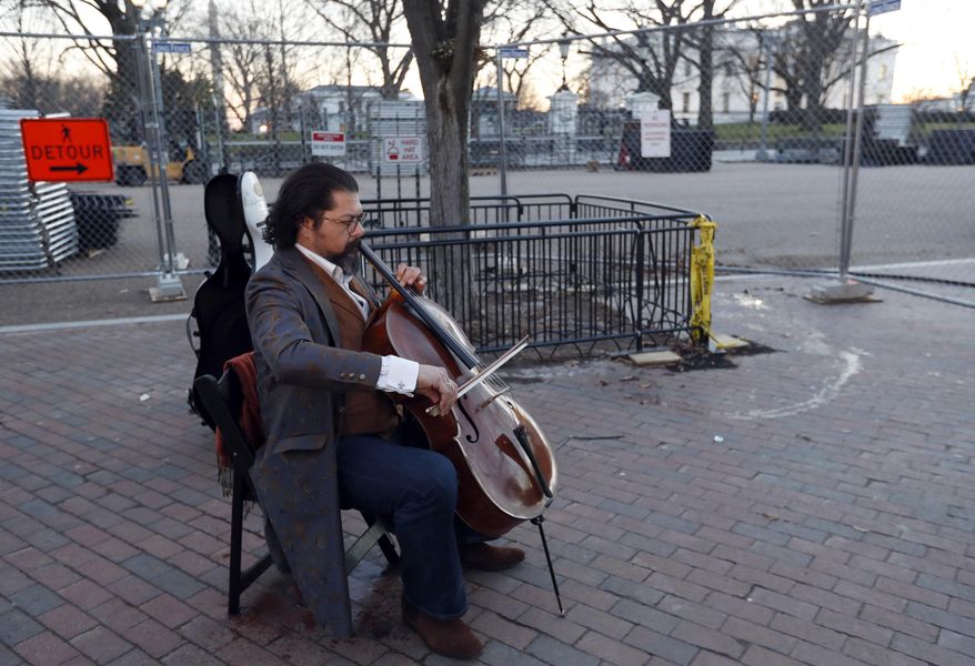 Karim Wasfi, the former conductor of the Baghdad Symphony, plays his cello is Lafayette Park near a protest about President Donald Trump's immigration policies, Wednesday, Jan. 25, 2017 in Washington. The half-Iraqi, half-Egyptian cellist and founder of an organization called Peace Through Arts played serene classical tunes. (AP Photo/Alex Brandon)
