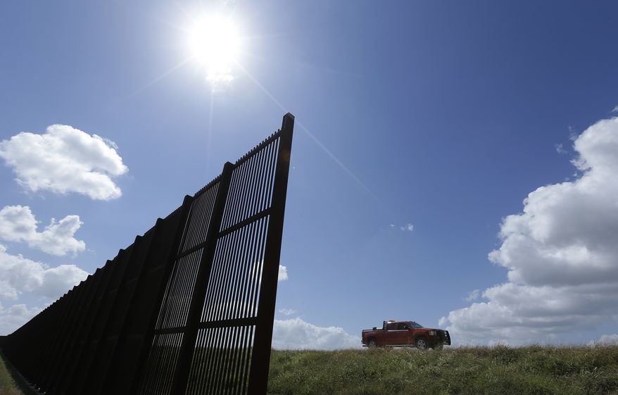 In this Sept. 6, 2012, file photo, cotton farmer Teofilo "Junior" Flores drives his truck along the U.S.-Mexico border fence that passes through his property in Brownsville, Texas. (AP Photo/Eric Gay, File)