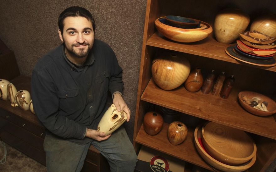 ADVANCE FOR USE SATURDAY, JAN. 28, 2017 AND THEREAFTER - In this Jan. 13, 2017 photo Jeremy Williams is seen with samples of his wood turning in Shelbyville, Ill. Williams' medium is dead wood, and that wood is often twisted, holed and decorated by the ravages of disease that he turns into artsy shapes and patterning. (Jim Bowling/Herald & Review via AP)