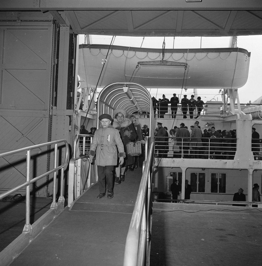 FILE - In this Dec. 29, 1965 file photo, passengers disembark from the Polish ship M.S. Batory, the first immigrant ship to dock in Boston in 20 years, as others wait for clearance on the deck. Some 450 immigrants from Iron Curtain countries and 200 tourists were aboard the vessel when it docked Dec. 29, 1965. Most of the immigrants are bound for Detroit and Chicago. Immigration to the U.S. has come in swells and dips over the past two-plus centuries, driven by shifts in U.S. policy, the mood in the country and world events. Labor shortages, racial tension, economic forces, religious prejudice and national security concerns all fit into the picture. (AP Photo/Bill Chaplis, File)
