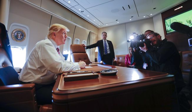 President Donald Trump sits at his desk on Air Force One upon his arrival at Andrews Air Force Base, Md., Thursday, Jan. 26, 2017. At the center is  Chief of Staff Reince Priebus. (AP Photo/Pablo Martinez Monsivais)