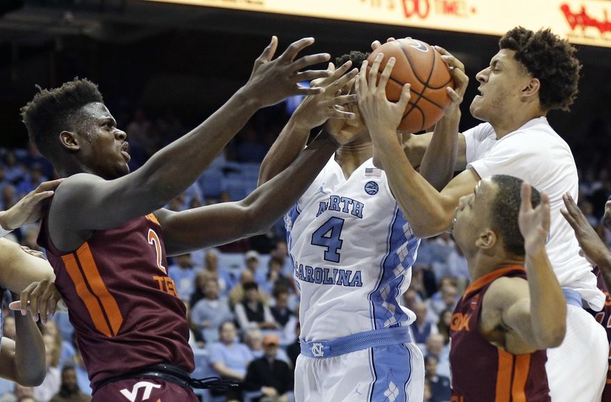 North Carolina's Isaiah Hicks (4) and Justin Jackson, right, struggle for possession of the ball with Virginia Tech's Khadim Sy (2) and Justin Robinson, right, during the first half of an NCAA college basketball game in Chapel Hill, N.C., Thursday, Jan. 26, 2017. (AP Photo/Gerry Broome)