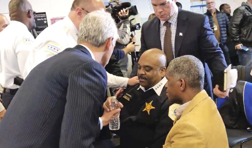 In this photo taken from video, Chicago Mayor Rahm Emanuel, left, hands a bottle of water to Police Superintendent Eddie Johnson after Johnson became wobbly during a news conference Friday, Jan. 27, 2017 in Chicago. The Chicago Sun-Times reports that there were requests for candy for Johnson as he fell ill. The news conference was halted as Johnson was attended to and an ambulance and a fire truck arrived. (Fran Spielman/Chicago Sun-Times via AP)