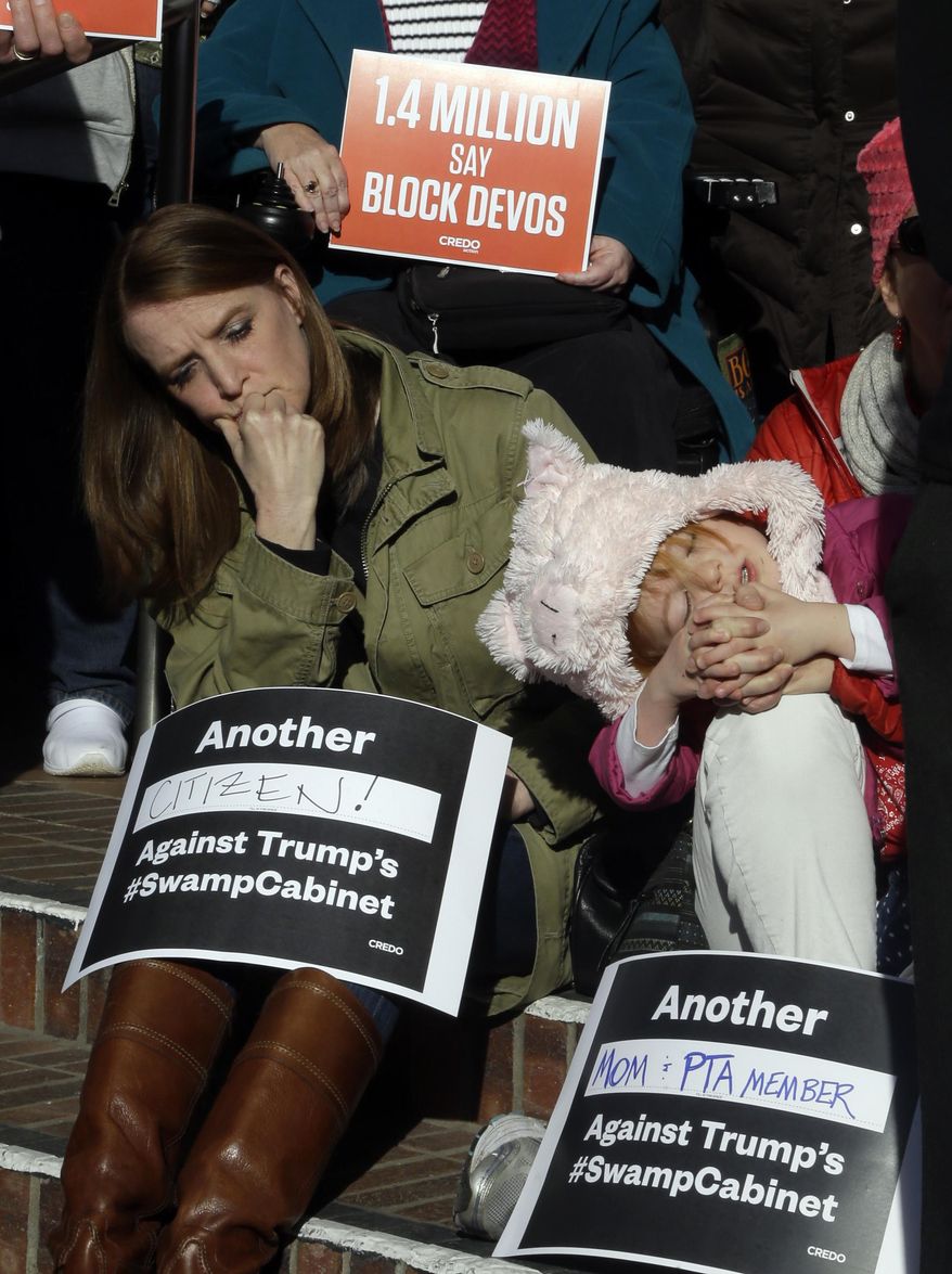 Britney Marr, left, listens to speakers as 4-year-old Miriam Haskey sleeps in her mother's arms during a rally in Portland, Ore., Friday, Jan. 27, 2017. Several hundred supporters gathered with Oregon congressional leaders in protest against Education Secretary nominee Betsy DeVos. (AP Photo/Don Ryan)