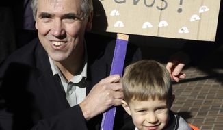 Sen. Jeff Merkley, D-Ore., left, poses with Asher Kockler and his sign for a family member during a rally in Portland, Ore., Friday, Jan. 27, 2017. Several hundred supporters gathered with Oregon congressional leaders in protest against Education Secretary nominee Betsy DeVos. (AP Photo/Don Ryan)