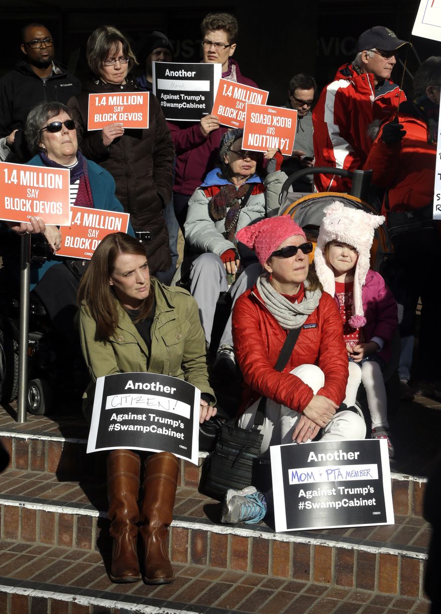 People hold signs as they listen to speakers during a rally in Portland, Ore., Friday, Jan. 27, 2017. Several hundred supporters gathered with Oregon congressional leaders in protest against Education Secretary nominee Betsy DeVos. (AP Photo/Don Ryan)