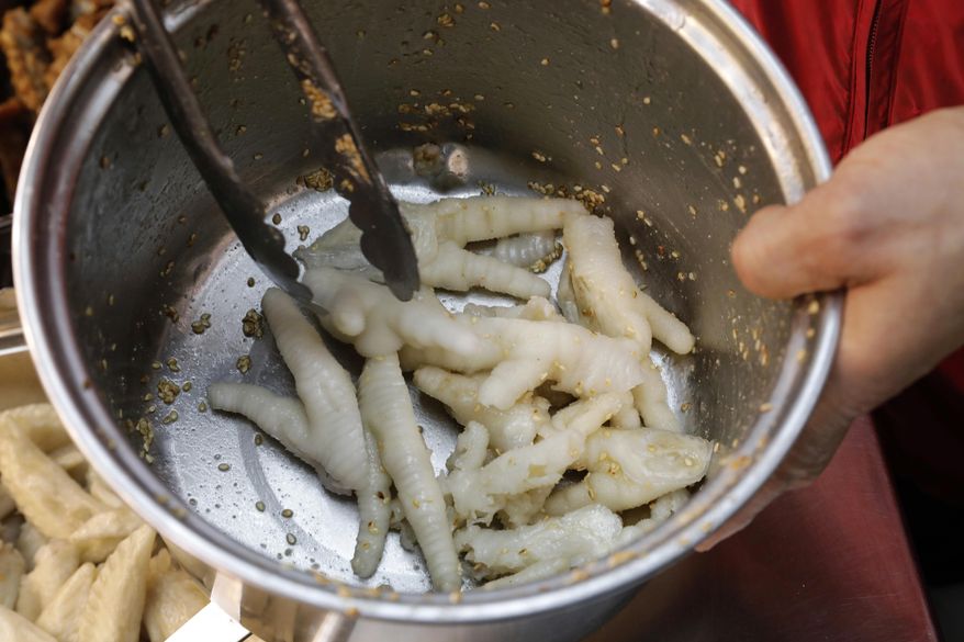 In this Monday, Jan. 23, 2017 photo, chicken feet snacks shop owner Leung Kin-kung mixes chicken feet with seasonings in Hong Kong. Saturday marks the start of the lunar Year of the Rooster and families in China will reunite for festivities, fireworks and food. While tradition calls for feasting on “auspicious” foods, many will also munch on staple snacks like “phoenix claws,” the Chinese name for chicken feet. (AP Photo/Vincent Yu)