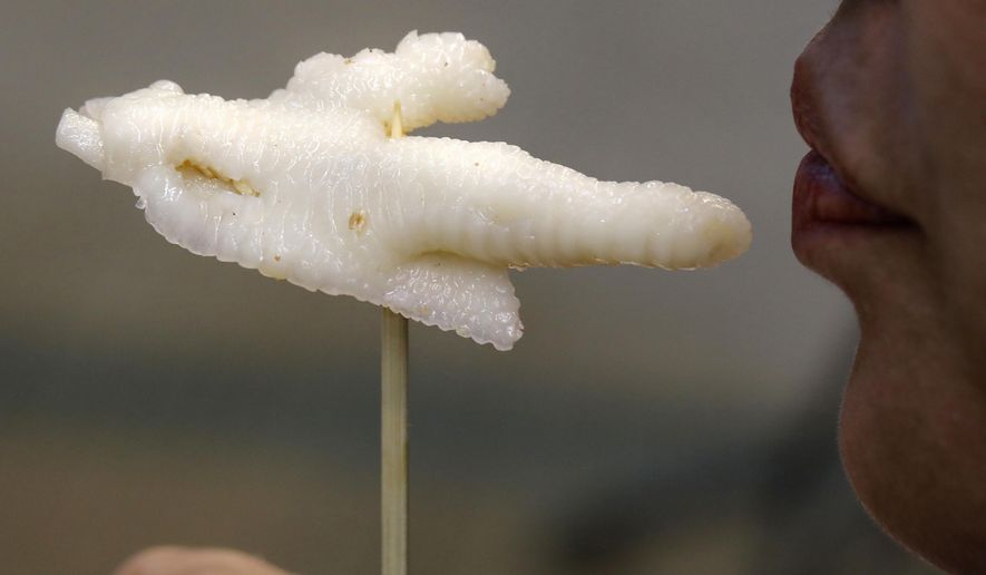 In this Monday, Jan. 23, 2017 photo, chicken feet snacks shop owner Leung Kin-kung testes a chicken feet in Hong Kong. Saturday marks the start of the lunar Year of the Rooster and families in China will reunite for festivities, fireworks and food. While tradition calls for feasting on “auspicious” foods, many will also munch on staple snacks like “phoenix claws,” the Chinese name for chicken feet. (AP Photo/Vincent Yu)