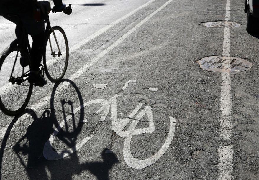 A bicyclist rides in the bike lane Friday, Jan. 27, 2017 in Minneapolis. As conflict between motorists and cyclists happens, a Republican state lawmaker wants to require cyclists to go through a safety training program and pay for a permit to use the protected bike lanes. (AP Photo/Jim Mone)