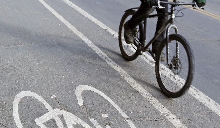 A bicyclist rides in the bike lane Friday, Jan. 27, 2017 in Minneapolis. As But conflict between motorists and cyclists happens, a Republican state lawmaker wants to require cyclists to go through a safety training program and pay for a permit to use those bike lanes. (AP Photo/Jim Mone)