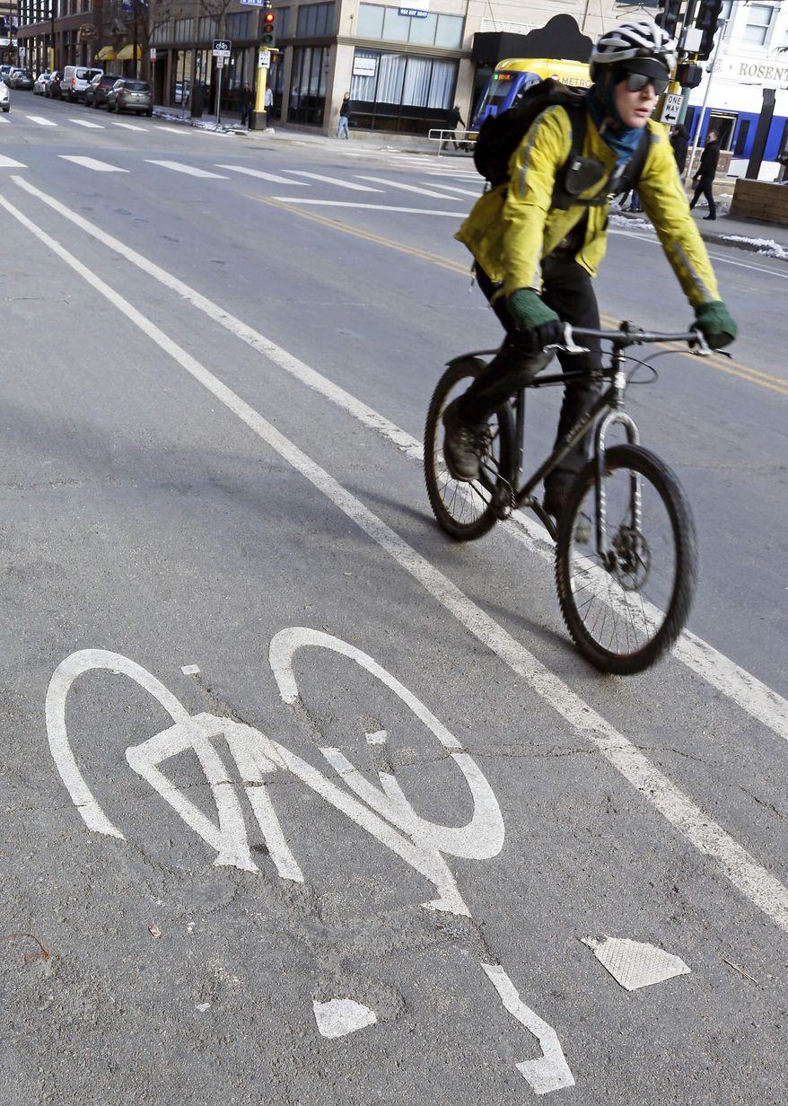 A bicyclist rides in the bike lane Friday, Jan. 27, 2017 in Minneapolis. As But conflict between motorists and cyclists happens, a Republican state lawmaker wants to require cyclists to go through a safety training program and pay for a permit to use those bike lanes. (AP Photo/Jim Mone)