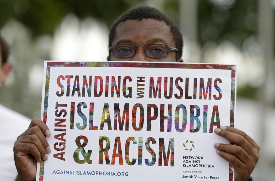 Protester Gregory Saint-Jean holds a sign during a rally against President Donald Trump's executive order on Muslim immigration, Thursday, Jan. 22, 2017, in downtown Miami. Protesters manifested their opposition to Trump's executive order restricting immigration from some Middle Eastern and African countries. (AP Photo/Alan Diaz)