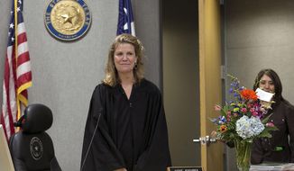 FILE - In this Feb. 29, 2016, file photo, District Judge Julie Kocurek, here making her first public appearance after spending weeks recovering from an assassination attempt in November 2015, is welcomed back to the bench in Austin, Texas. Travis County officials are considering a $500,000 payment to Kocurek to avoid a potential lawsuit claiming authorities didn&#39;t do enough to prevent a shooting that left the judge seriously wounded. (Ralph Barrera/Austin American-Statesman via AP, File)