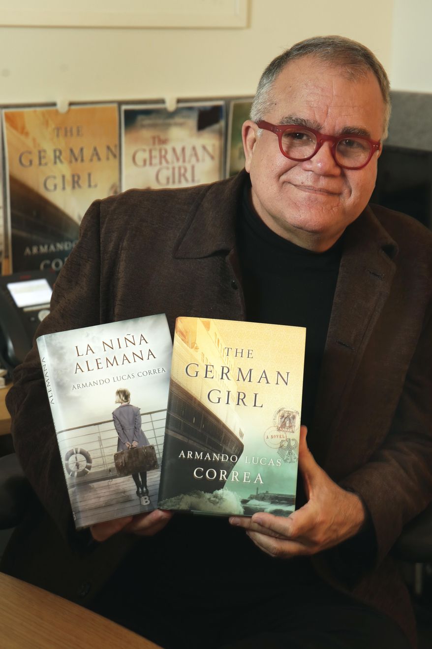 Armando Correa, Editor in Chief of People en Espanol, poses with the Spanish and English versions of his novel, "The German Girl," in his office in New York, Tuesday, Jan. 24, 2017. (AP Photo/Richard Drew)