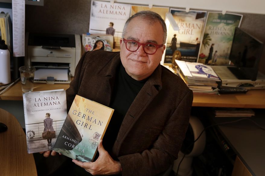Armando Correa, Editor in Chief of People en Espanol, poses with the Spanish and English versions of his novel, "The German Girl," in his office in New York, Tuesday, Jan. 24, 2017. (AP Photo/Richard Drew)