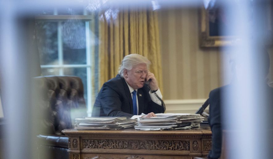 President Donald Trump is shown here speaking on the phone with German Chancellor Angela Merkel, Saturday, Jan. 28, 2017, in the Oval Office at the White House in Washington. Mr. Trump also spoke with Japanese Prime Minister Shinzo Abe and is expected to talk with Russian President Vladimir Putin, French President Francois Hollande and Australian Prime Minister Malcolm Turnbull Saturday as well. (AP Photo/Andrew Harnik)