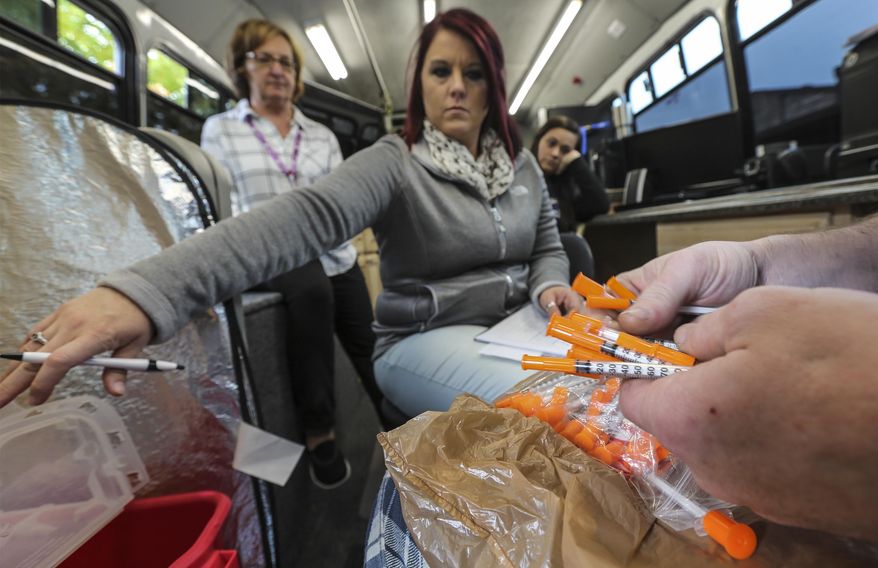 Amber Carmack watches as an intravenous drug user drops off used syringes in an RV in the parking lot at the Franklin County Health Department in Franklin County, Ky. Since state lawmakers decided in March 2015 to allow needle exchanges in Kentucky, 21 have been established. (Michael Clevenger/The Courier-Journal via AP) **FILE**