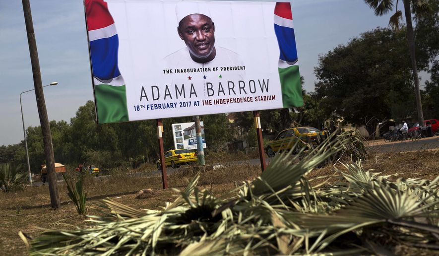 A billboard calling for the inauguration of Adam Barrow as president in Feb. 18 is set on the side of a road in Serrukunda, Gambia, Friday Jan. 27, 2017. Hundreds of thousands turned out Thursday to greet President Adama Barrow, a week after he took the oath of office in neighboring Senegal. (AP Photo/Jerome Delay)