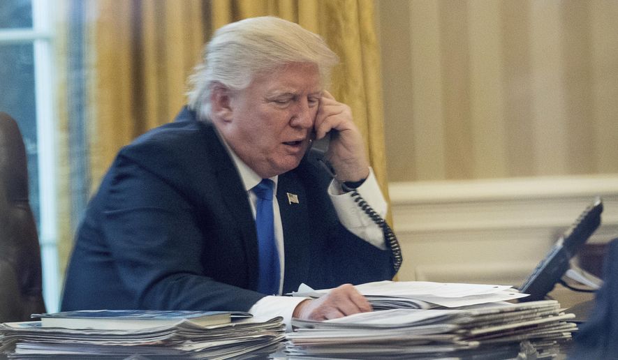 President Donald Trump speaks on the phone with German Chancellor Angela Merkel, Saturday, Jan. 28, 2017, in the Oval Office at the White House in Washington. (AP Photo/Andrew Harnik)