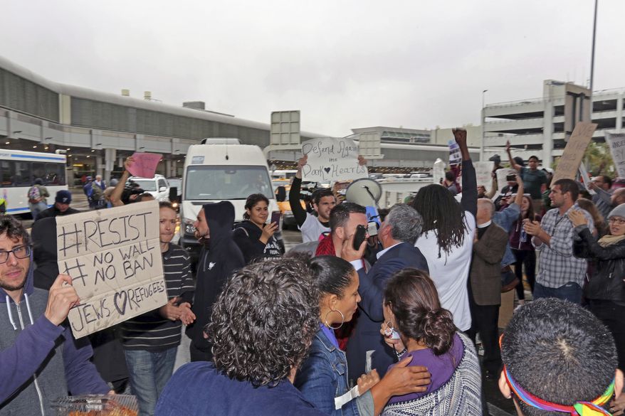 People demonstrating against President Trumps&#39;s new immmigration policy temporarily block the street at Miami International Airport for about 15 minutes and then were told to move back to the sidewalk by police on Sunday, Jan. 29, 2017.Trump’s immigration order sowed more confusion and outrage across the country Sunday, with travelers detained at airports, panicked families searching for relatives and protesters registering their opposition to the sweeping measure. (C.M. Guerrero/El Nuevo Herald via AP)