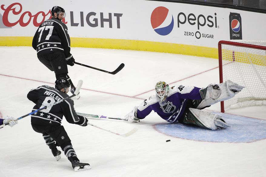 Pacific Division's Joe Pavelski(8), of the San Jose Sharks, shoots to score against Central Division goalie Devan Dubnyk, of the Minnesota Wild, as teammate Jeff Carter(77), of the Los Angeles Kings, watches during the NHL hockey All-Star game, Sunday, Jan. 29, 2017, in Los Angeles. (AP Photo/Jae C. Hong)