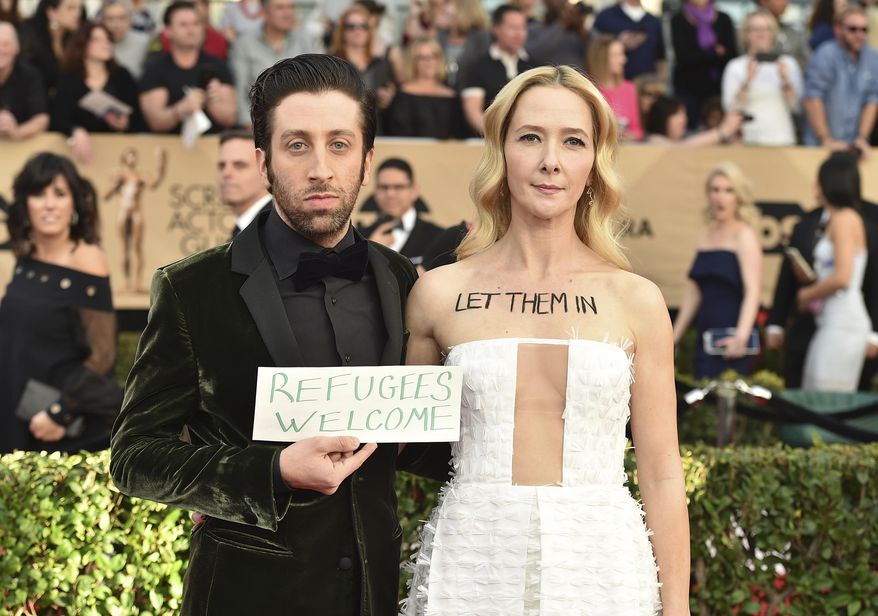 Simon Helberg, left, and Jocelyn Towne display protest signs against the U.S. policy of temporarily barring refugees and citizens of seven predominantly Muslim countries, at the 23rd annual Screen Actors Guild Awards at the Shrine Auditorium & Expo Hall on Sunday, Jan. 29, 2017, in Los Angeles. (Photo by Jordan Strauss/Invision/AP)