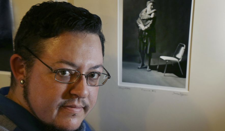 In this Jan. 25, 2017 photo, artist Jeff Kramer poses next to one of his self-portraits entitled "The Gender Series," a part of the group exhibit "This is What TRANS Feels Like" at Wrong Brain Art Collective in Dover, N.H. Kramer said he wants people to see that gender is based on a spectrum and that roles keep changing. The exhibit runs through Feb. 14. (AP Photo/Elise Amendola)