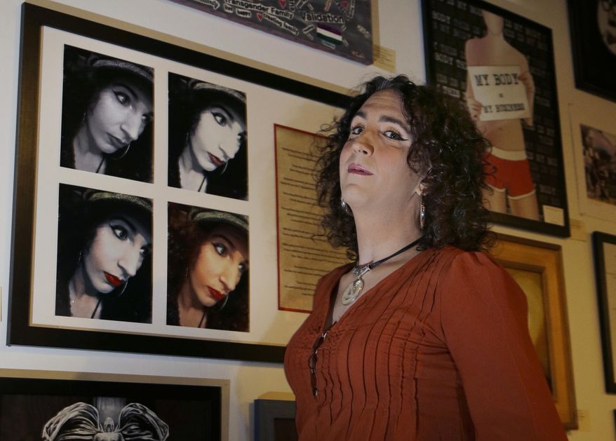In this Jan. 25, 2017 photo, artist Chloe LaCasse poses next to her self-portraits and poetry entitled "Red Lips," a part of the group exhibit "This is What TRANS Feels Like" at Wrong Brain Art Collective in Dover, N.H. The exhibit runs through Feb. 14. (AP Photo/Elise Amendola)
