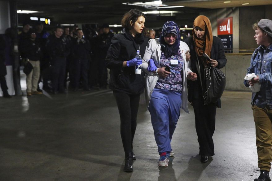 Saffiya Hrahsheh, center, is helped away from police by Liz Bates, left, and others after being pepper sprayed as police made their final dispersal of protesters out to the parking garage as about 3,000 people gather at Seattle-Tacoma International Airport in Seattle, Sunday, Jan. 29, 2017, to protest President Donald Trump's order that restricts immigration to the U.S. Trump signed an executive order Friday that bans legal U.S. residents and visa-holders from seven Muslim-majority nations from entering the U.S. for 90 days and puts an indefinite hold on a program resettling Syrian refugees. (Genna Martin/seattlepi.com via AP)