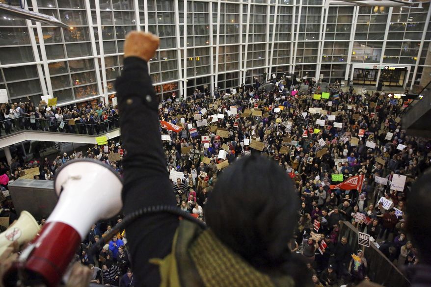 Seattle city councilwoman and socialist activist Kshama Sawant raises a fist over the crowd, as more than 1,000 people gather at Seattle-Tacoma International Airport, to protest President Donald Trump's order that restricts immigration to the U.S., Saturday, Jan. 28, 2017, in Seattle. President Trump signed an executive order Friday that bans legal U.S. residents and visa-holders from seven Muslim-majority nations from entering the U.S. for 90 days and puts an indefinite hold on a program resettling Syrian refugees. (Genna Martin/seattlepi.com via AP)