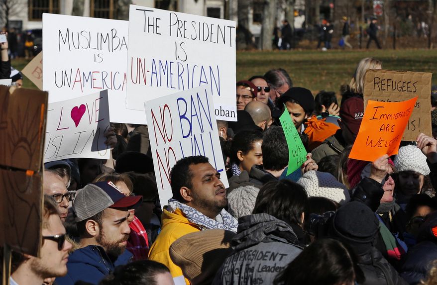 Protesters at an immigrants' rights rally hold signs while listening to speakers Sunday, Jan. 29, 2017, in Battery Park, in New York as President Donald Trump's immigration order sowed more chaos and outrage across the country. Travelers were detained at airports, while panicked families searched for relatives. These protesters registered opposition to the president's sweeping measure that was blocked by several federal courts. (AP Photo/Kathy Willens)