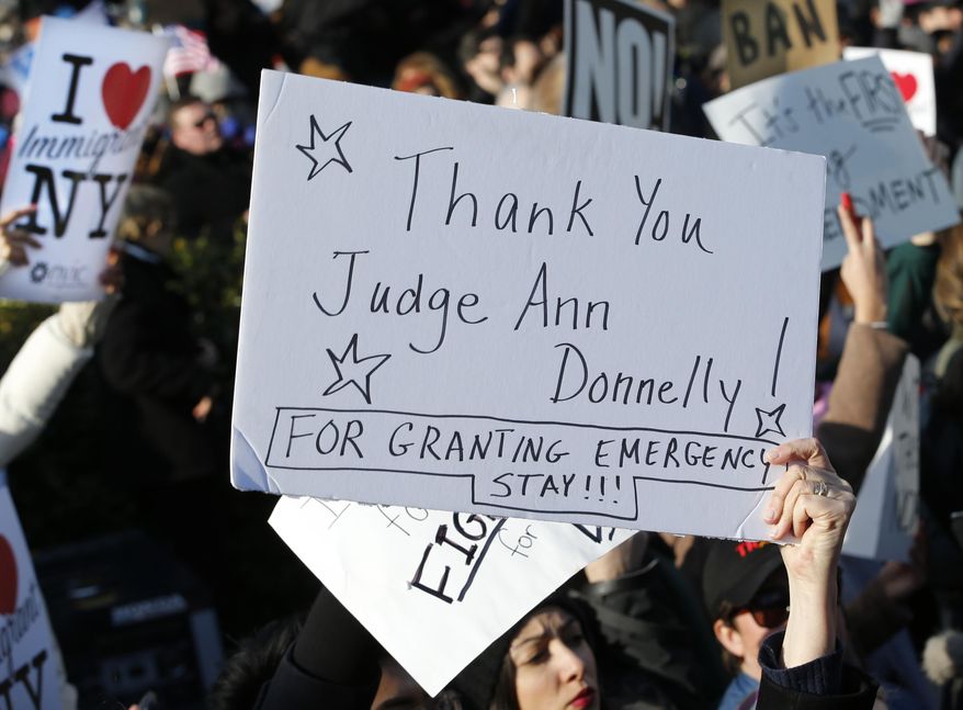 A woman holds a sign acknowledging a stay affecting immigrants trying to reach the United States issued late Saturday by New York Federal Judge Ann M. Donnelly, as they protest President Donald Trump's executive order banning immigrants from certain countries, Sunday, Jan. 29, 2017, in New York, as part of an immigrants' rights rally at Battery Park. (AP Photo/Kathy Willens)