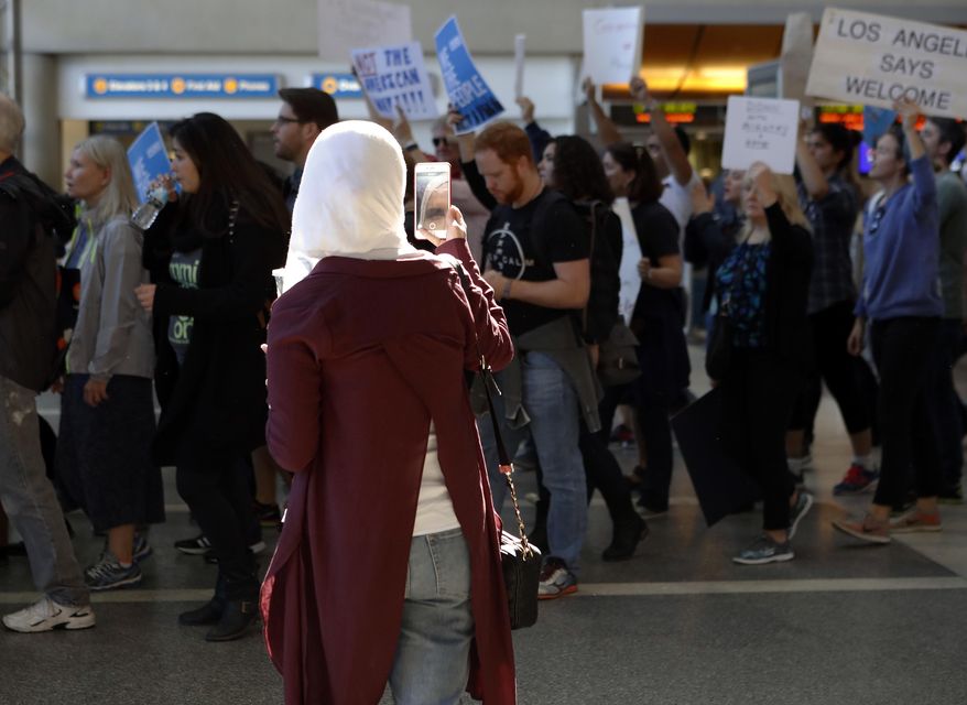 A traveler records demonstrators as they march through Tom Bradley International Terminal as protests against President Donald Trump's executive order banning travel from seven Muslim-majority countries continue at Los Angeles International Airport Sunday, Jan. 29, 2017. (AP Photo/Ryan Kang)