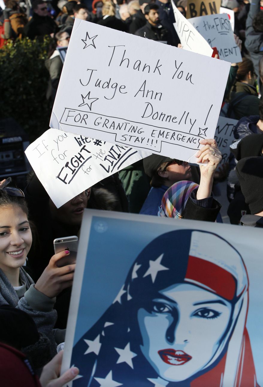 A woman snaps a cell phone photo as others hold up signs acknowledging the federal stay affecting immigrants trying to reach the United States issued by New York federal judge Ann M. Donnelly, Sunday, Jan. 29, 2017, in New York during an immigrants' rights rally and protest at Battery Park. President Donald Trump's immigration order sowed more chaos and outrage across the country Sunday, with travelers detained at airports, panicked families searching for relatives and protesters registering opposition to the sweeping measure that was blocked by several federal courts. (AP Photo/Kathy Willens)