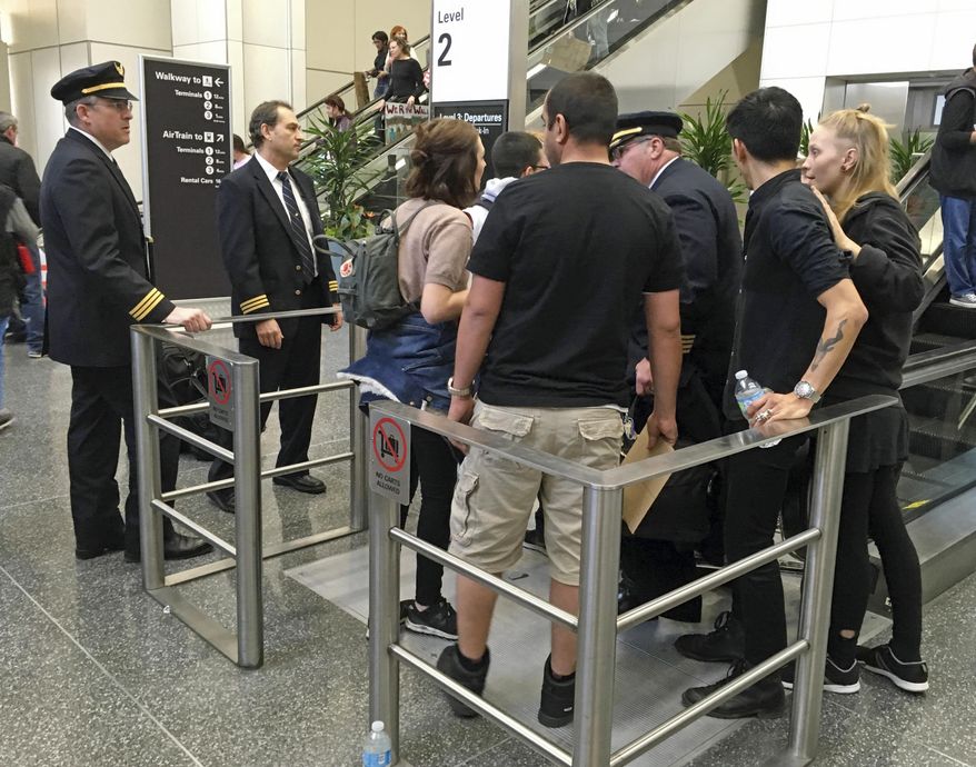 Demonstrators block the way for flight crew members, two at left and one at center right, from proceeding at the international terminal as people protest against President Donald Trump's executive order banning travel to the U.S. by citizens of several countries at San Francisco International Airport, Sunday, Jan. 29, 2017. (AP Photo/Olga Rodriguez)