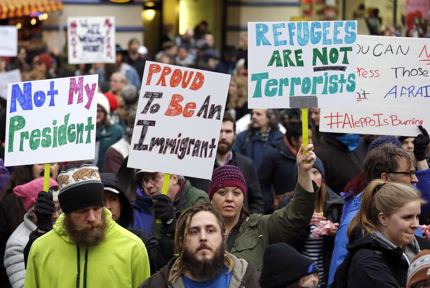 People begin to gather before a rally protesting President Donald Trump's travel ban on refugees and citizens of seven Muslim-majority nations, Sunday, Jan. 29, 2017, in Seattle. (AP Photo/Elaine Thompson)