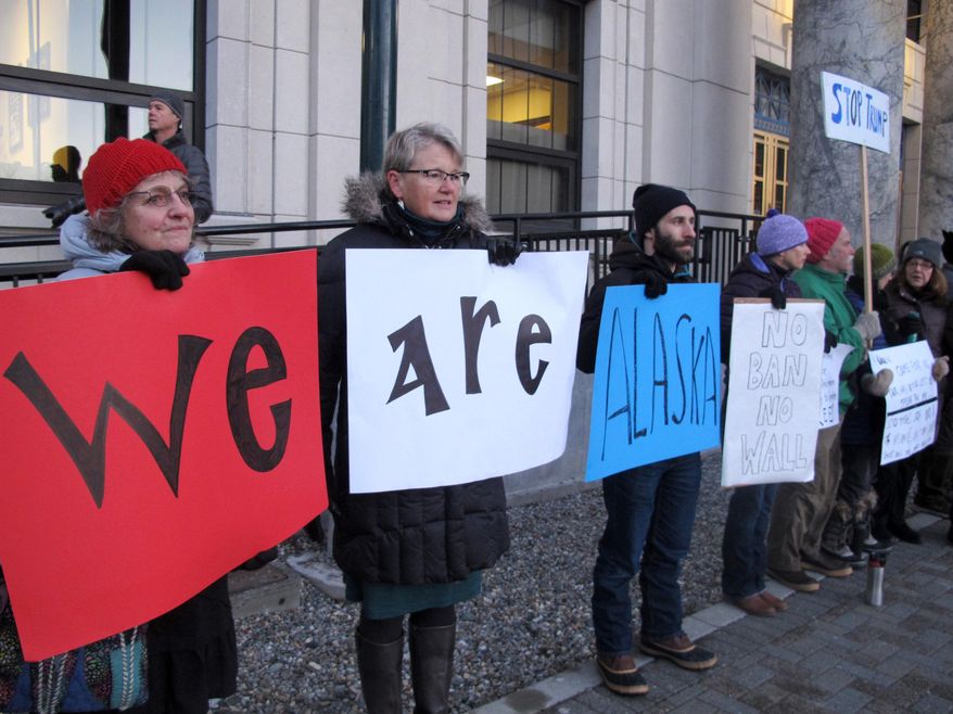 Demonstrators gather in front of the Alaska Capitol on Monday, Jan. 30, 2017, in Juneau, Alaska, to protest President Donald Trump's executive order temporarily suspending immigration from seven countries and the United States' refugee program. Holdings signs spelling out We Are Alaska are, from left to right, Jane Edwards, Fabienne Peter-Contesse and Dan DeSloover. (AP Photo/Becky Bohrer)