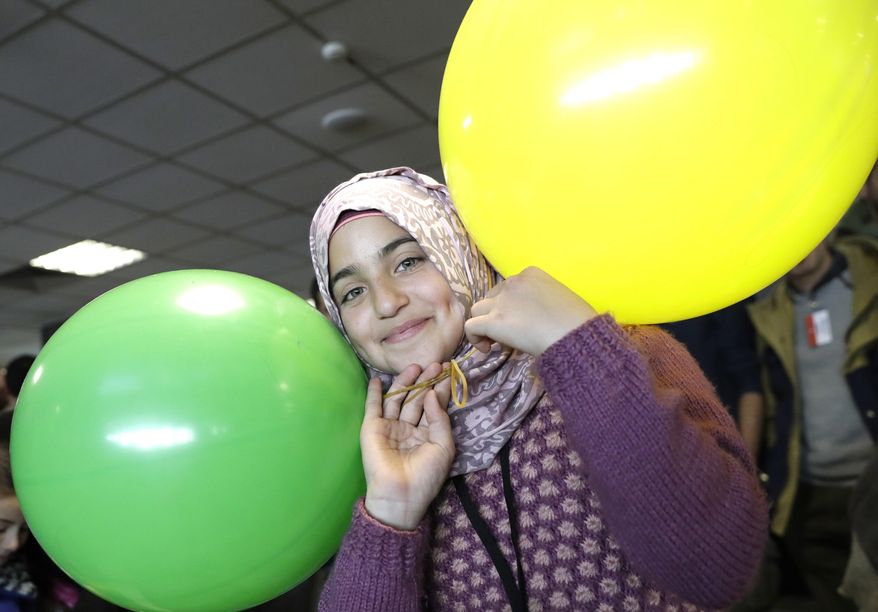 Haya, a 13 year-old Syrian refugee from Homs, plays with balloons upon her arrival at Rome's Fiumicino international airport, Monday, Jan. 30, 2017. Italian government and church officials have welcomed 41 Syrian refugees at Rome's airport, saying they wanted to show solidarity at a time when the United States is sending refugees away and building walls to keep them out. (AP Photo/Alessandra Tarantino)