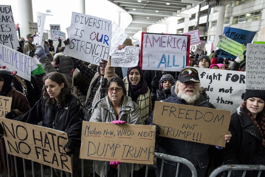Demonstrators hold signs and chant during a protest against President Donald Trump&#39;s executive order banning travel to the United States by citizens of several countries Sunday, Jan. 29, 2017, at Detroit Metropolitan Airport. (Jeffrey M. Smith/The Times Herald via AP)