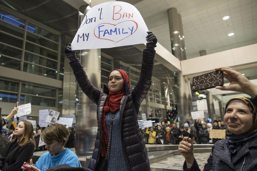 Demonstrators hold signs and chant in the baggage claim area during a protest against President Donald Trump's executive order banning travel to the United States by citizens of several countries Sunday, Jan. 29, 2017, at Detroit Metropolitan Airport. (Jeffrey M. Smith/The Times Herald via AP)