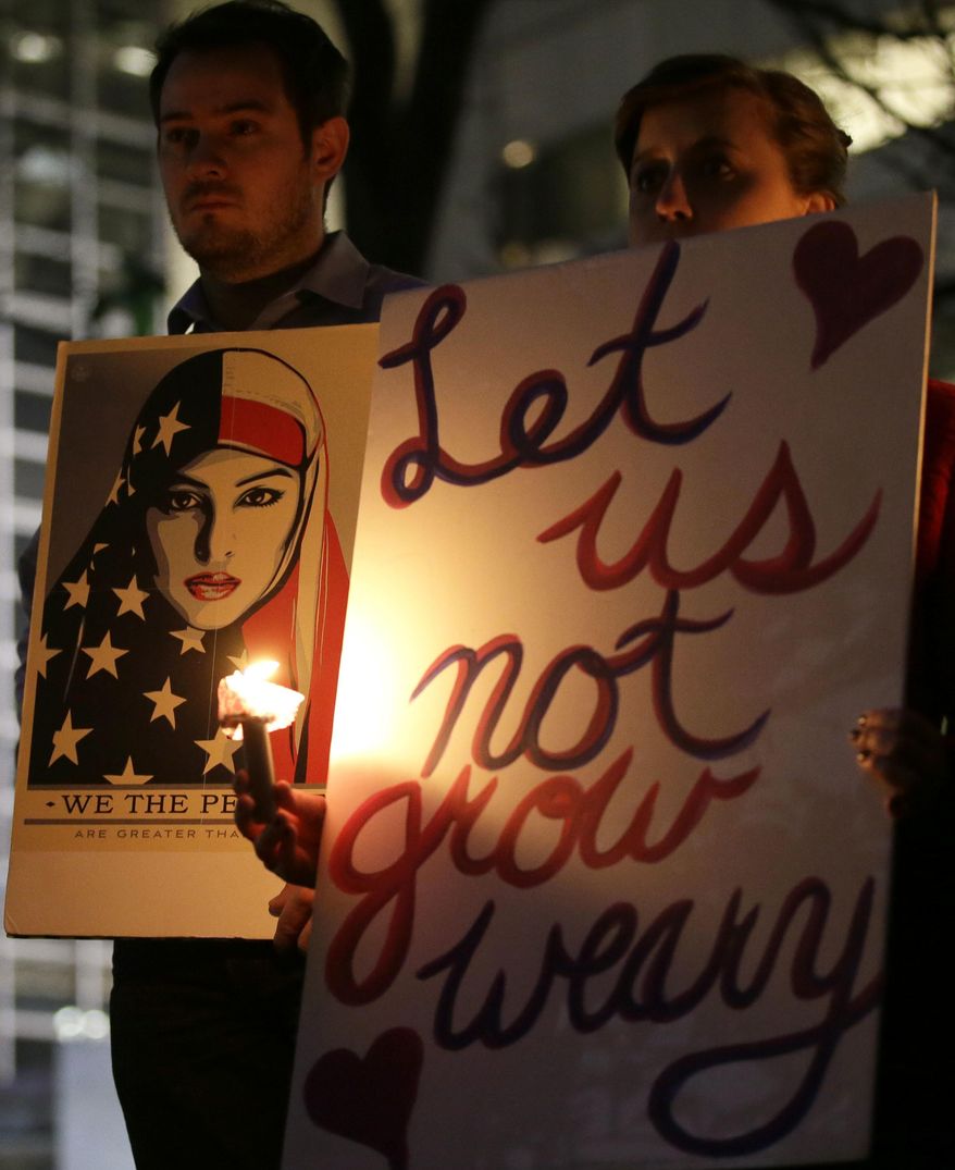 People holds signs during a candlelight vigil at Thanksgiving Square in downtown Dallas, Monday, Jan. 30, 2017. People gathered to protest against President Donald Trump's executive order temporarily banning immigrants from seven Muslim-majority countries from entering the U.S. and suspending the nation’s refugee program. (AP Photo/LM Otero)