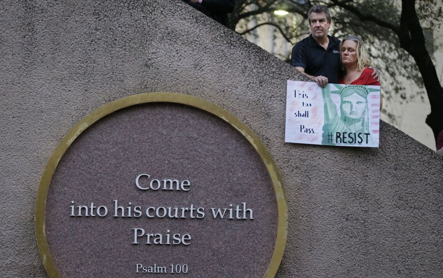 Sammantha Hall and her husband Jay hold a sign before a candlelight vigil at Thanksgiving Square in Dallas, Monday, Jan. 30, 2017. People gathered to protest against President Donald Trump's executive order temporarily banning immigrants from seven Muslim-majority countries from entering the U.S. and suspending the nation’s refugee program. (AP Photo/LM Otero)
