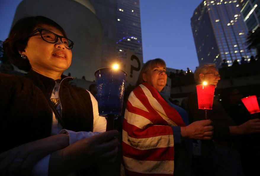 Yeon Quinn, left, and Sue Maienschein hold candles during a vigil at Thanksgiving Square in downtown Dallas, Monday, Jan. 30, 2017. People gathered to protest against President Donald Trump's executive order temporarily banning immigrants from seven Muslim-majority countries from entering the U.S. and suspending the nation’s refugee program. (AP Photo/LM Otero)