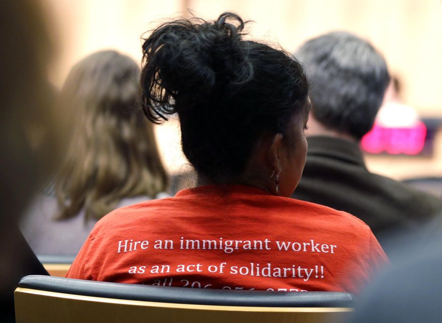 A woman wears a shirt that reads "Hire an immigrant worker as an act of solidarity!!" Monday, Jan. 30, 2017, as she attends a Seattle City Council meeting in Seattle. Council members passed a resolution Monday reaffirming that Seattle is a "welcoming city" that treats residents equally regardless of their refugee or immigration status. (AP Photo/Ted S. Warren)