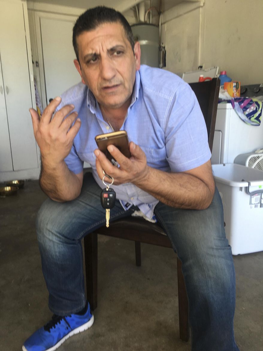 Iraqi refugee Raed Rabban, 49, speaks by phone from his garage in El Cajon, Calif., with his brother Luey Rabban, 47, in Baghdad, on Monday, Jan. 30, 2017. Rabban's younger brother, Luey, who works as cook in a Baghdad restaurant, received refugee status in the United States about eight months ago. Luey was waiting for his turn to emigrate but said Monday by phone he is unsure now if that day will ever come. (AP Photo/Eliott Spagat)