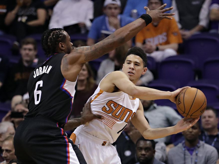 Phoenix Suns guard Devin Booker (1) passes around Los Angeles Clippers center DeAndre Jordan (6) during the first half of an NBA basketball game, Wednesday, Feb. 1, 2017, in Phoenix. (AP Photo/Matt York)