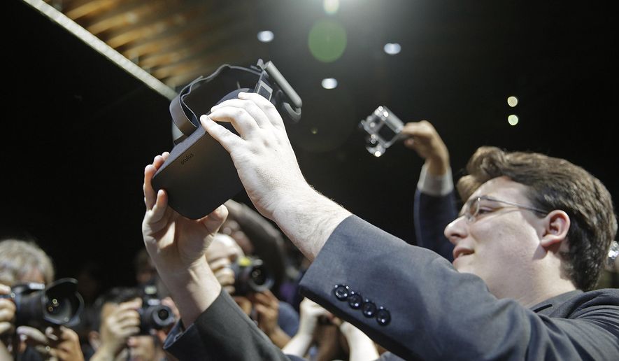 In this June 11, 2015, file photo, Oculus founder Palmer Luckey holds up the new Oculus Rift virtual reality headset for photographers following a news conference, in San Francisco. (AP Photo/Eric Risberg, File)