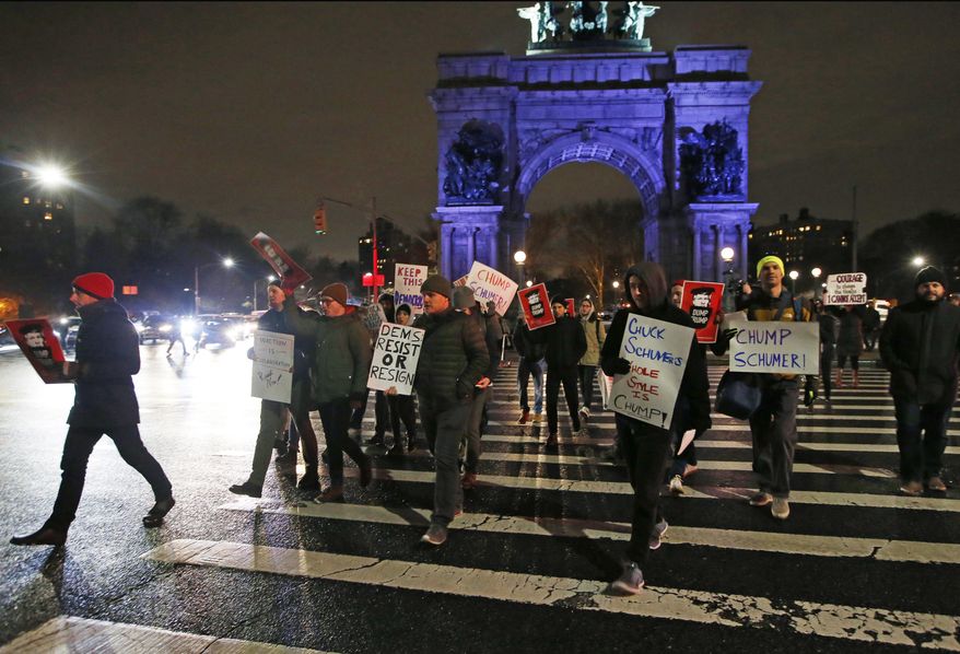 In this Tuesday, Jan. 31, 2017 photo, demonstrators protesting Senate Minority leader Chuck Schumer hold signs and chant as they march across the traffic circle at Brooklyn's Grand Army Plaza during a protest in New York. Liberals are vowing to put pressure on Schumer to mount a vigorous opposition to the agenda of President Donald Trump. (AP Photo/Kathy Willens)