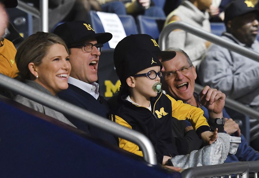 Sarah Harbaugh, Michigan coach Jim Harbaugh, son James and Jim's dad Jack Harbaugh sing during the Michigan fight song during the "Signing of the Stars" event on national signing day at Crisler Center in Ann Arbor, Mich., Wednesday, Feb. 1, 2017. (Daniel Mears/Detroit News via AP)