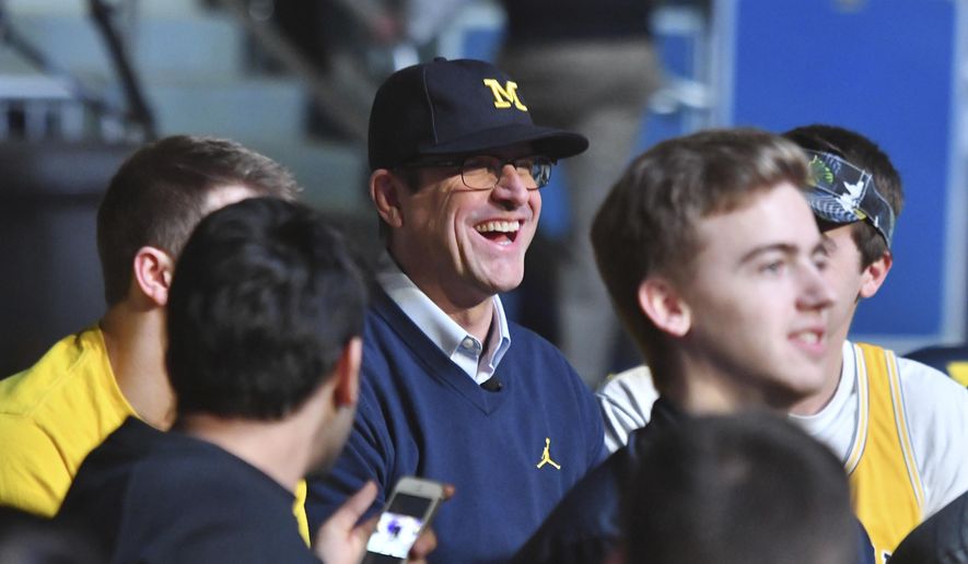 Michigan head football coach Jim Harbaugh sits with students before the "Signing of the Stars" event on national signing day at Crisler Center in Ann Arbor, Mich., Wednesday, Feb. 1, 2017. (Daniel Mears/Detroit News via AP)
